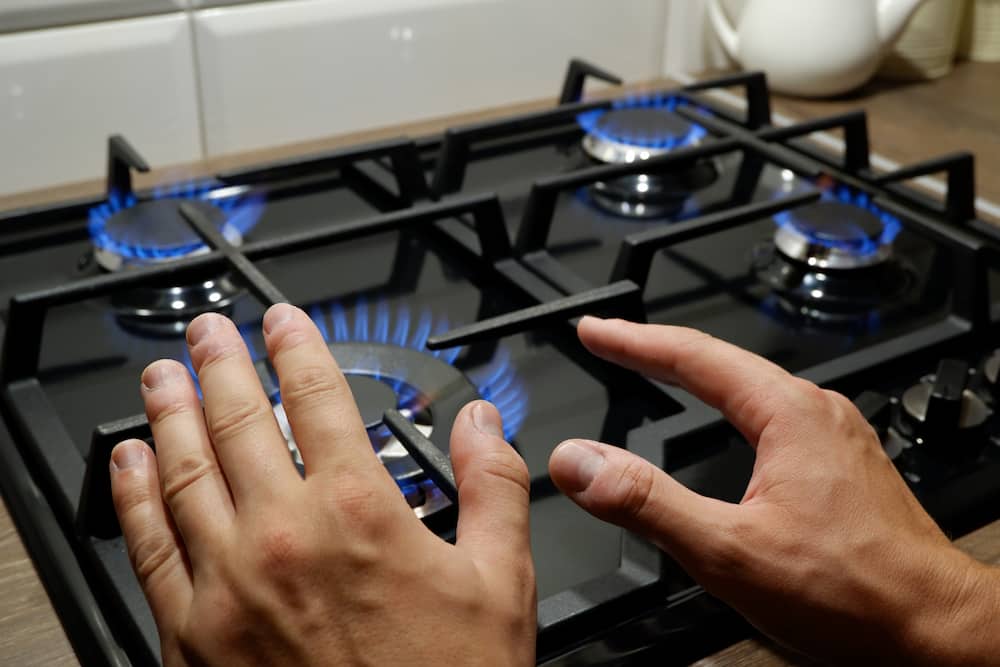 A person warming their hands over a gas lit stove.