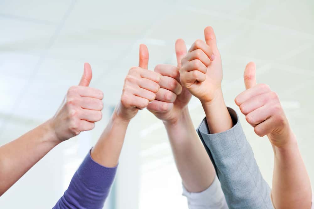 A group of hands up in the air with the thumbs up gesture